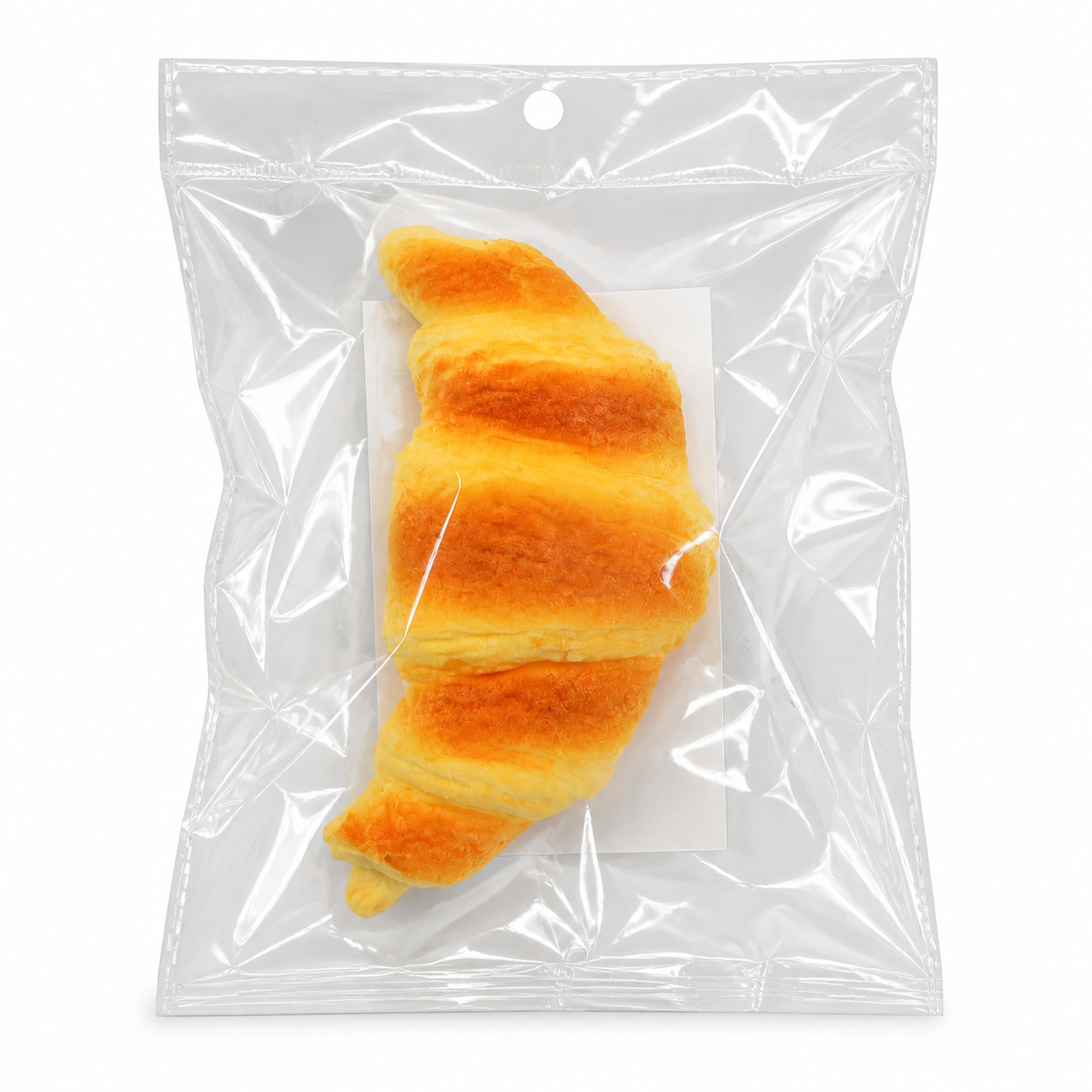 Croissant squishy toy in clear bag on white background